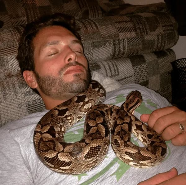Man sleeping with snake on his chest